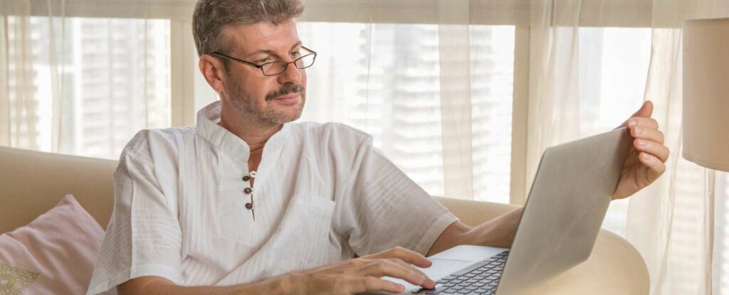 middle age man learning a new job on his computer while going through a midlife crisis