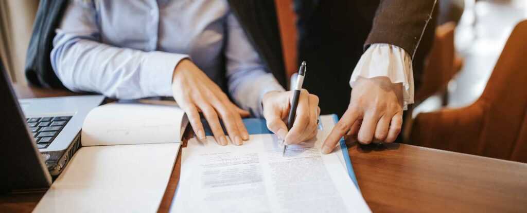 woman signing a traditional contract as an example of a smart contract