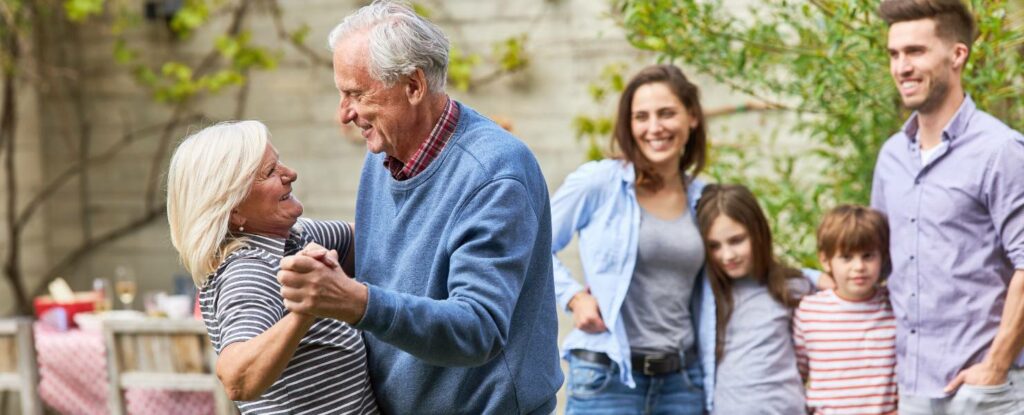 family happily watching older parents dance